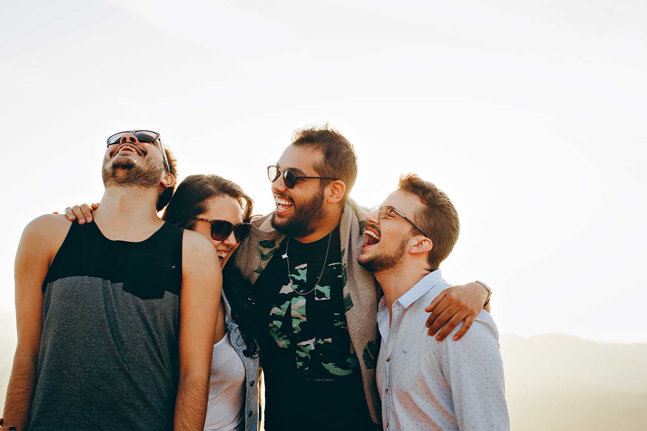 group of four friends embracing one another outside