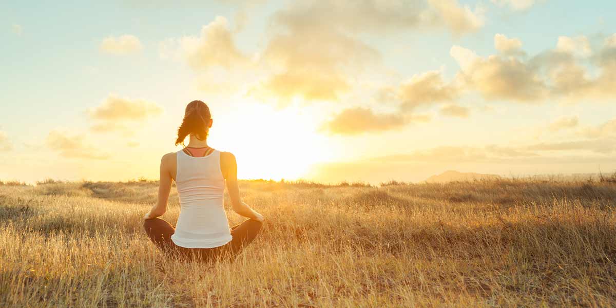 woman in recovery meditating outside in a meadow