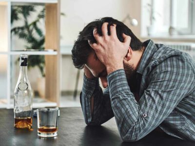 man sitting at a table with alcohol experiencing withdrawal