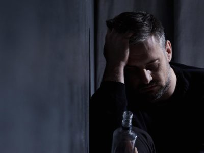 man having an alcoholic blackout next to a bottle of liquor