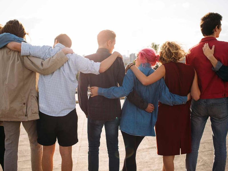 group of young people in recovery embracing each other on the beach