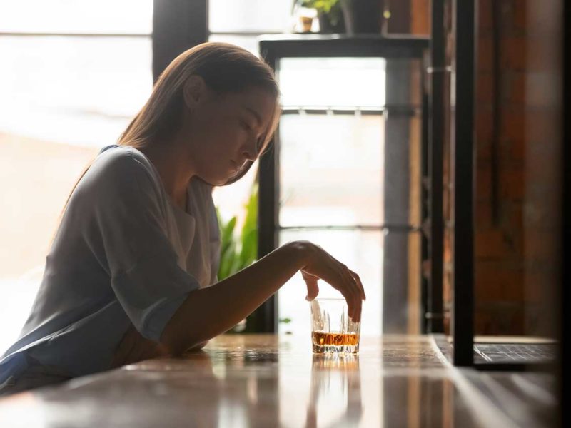 woman sitting at a bar with alcohol