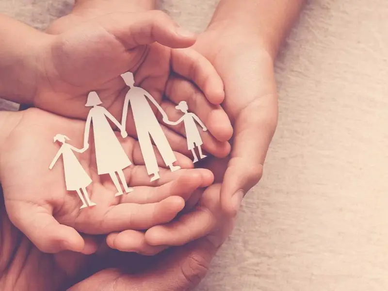 hands holding paper cutout of a family