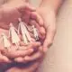 hands holding paper cutout of a family
