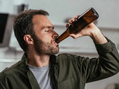 working man drinking beer in a brown bottle