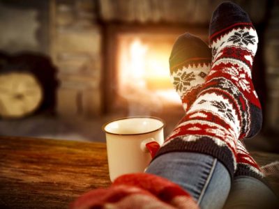 person wearing Christmas socks by a fireplace