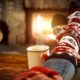 person wearing Christmas socks by a fireplace