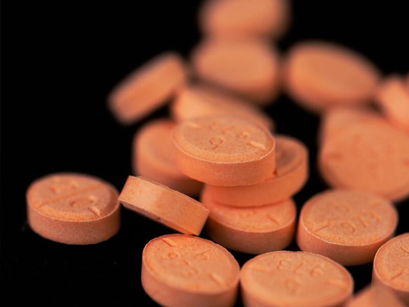 orange adderall pills on a black background