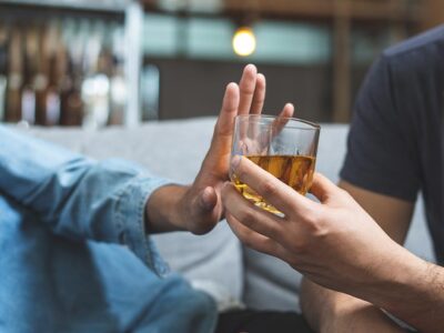 man saying no to a glass of alcohol and avoiding relapse