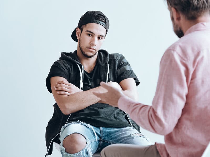 Young mand folding arms talking to a counseler