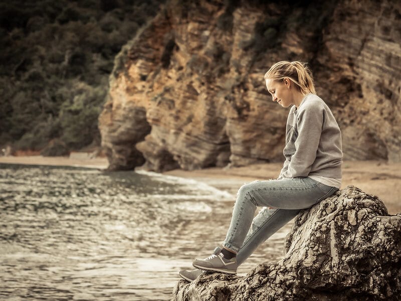sitting on rock near beach and water woman