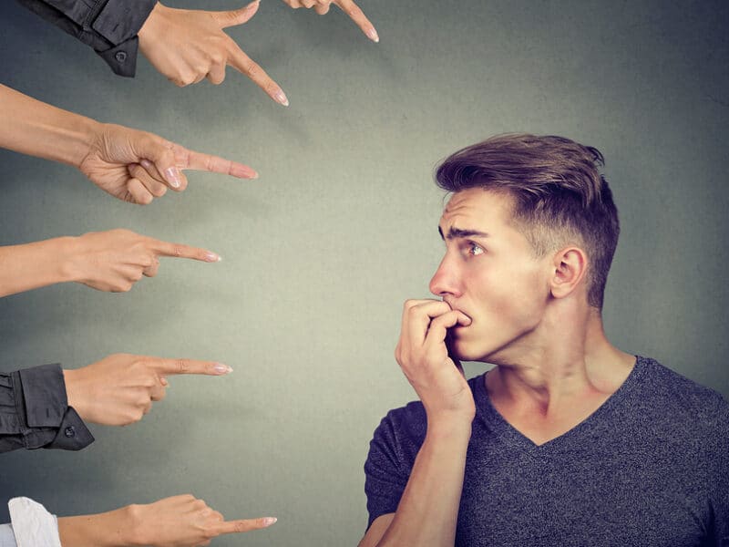 man with people hands pointing at him and he's worried