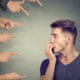 man with people hands pointing at him and he's worried