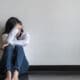 woman displaying signs of anxiety and stress while sitting against a wall.