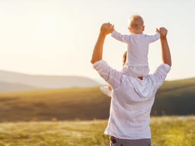 man carrying child on shoulders with nice view outdoors