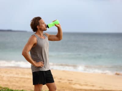 man hydrating at waterside on beach
