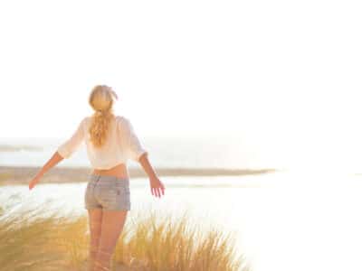 young blond lady facing the ocean