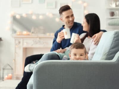 young couple with coffee mugs and child peeking over