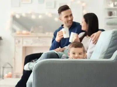 young couple with coffee mugs and child peeking over