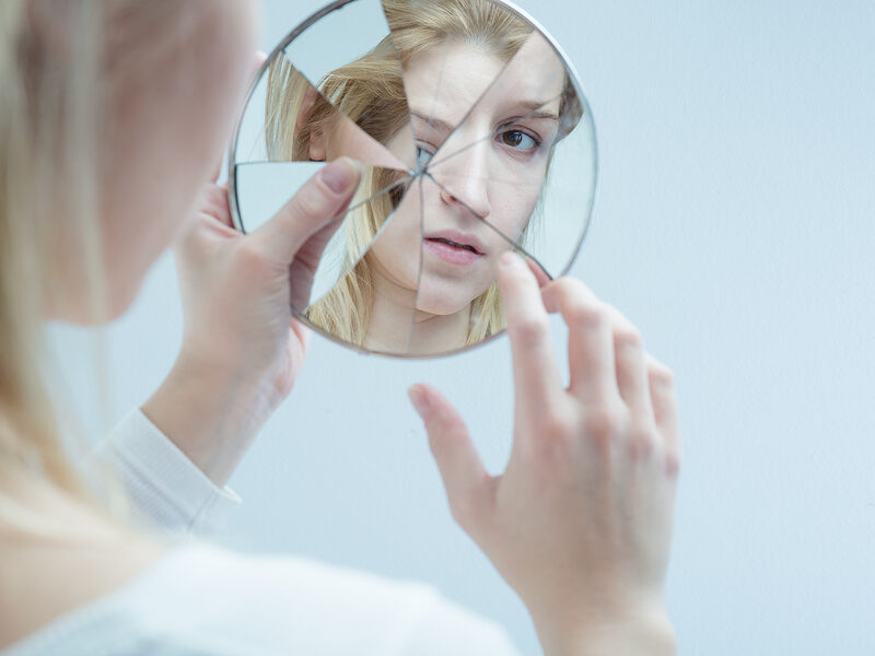 women looking in cracked makeup mirror