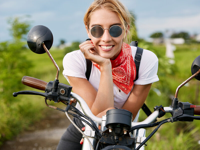 young lady with motorcycle posing outdoors