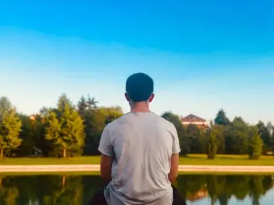 young man looking at small lake