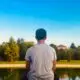 young man looking at small lake