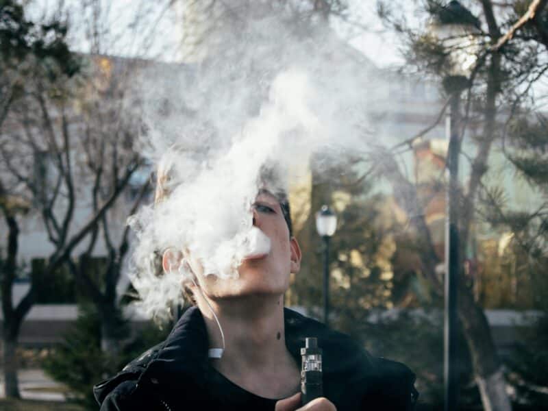 teen blowing a cloud of smoke from vaping.