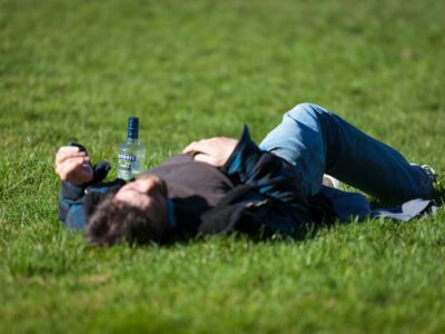 A man is laying in a field, blacked out from alcohol