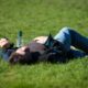 A man is laying in a field, blacked out from alcohol