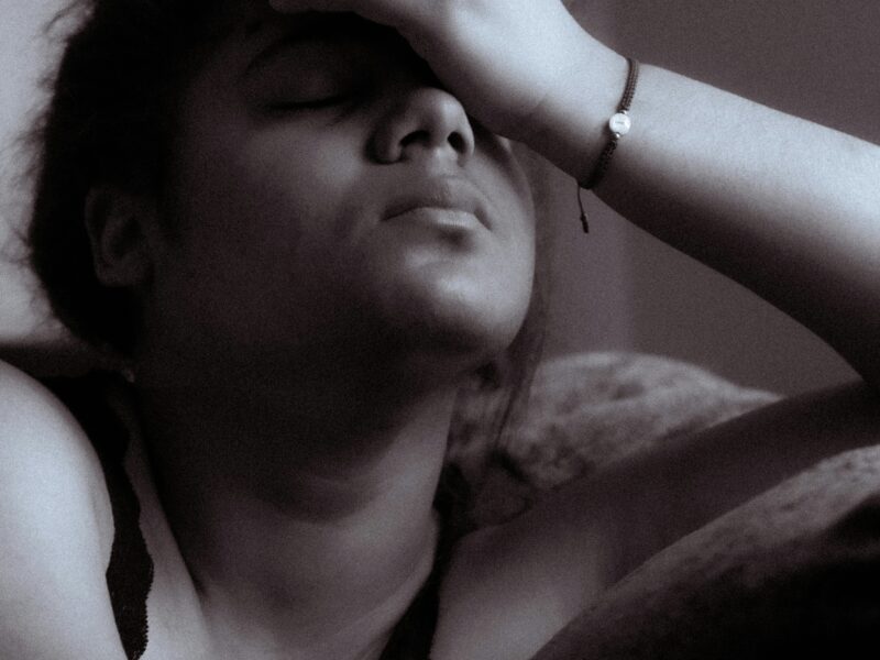 woman in the dark clearly in pain, holding her head.