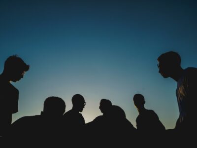 a group of individuals shrouded in darkness, symbolizing the dangers of peer pressure