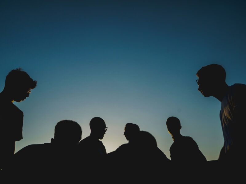 a group of individuals shrouded in darkness, symbolizing the dangers of peer pressure