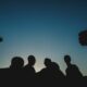 a group of individuals shrouded in darkness, symbolizing the dangers of peer pressure