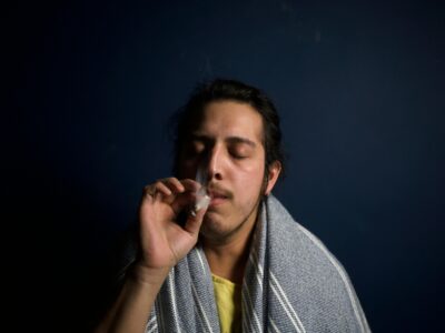 A man with a towel wrapped around his head smoking a joint