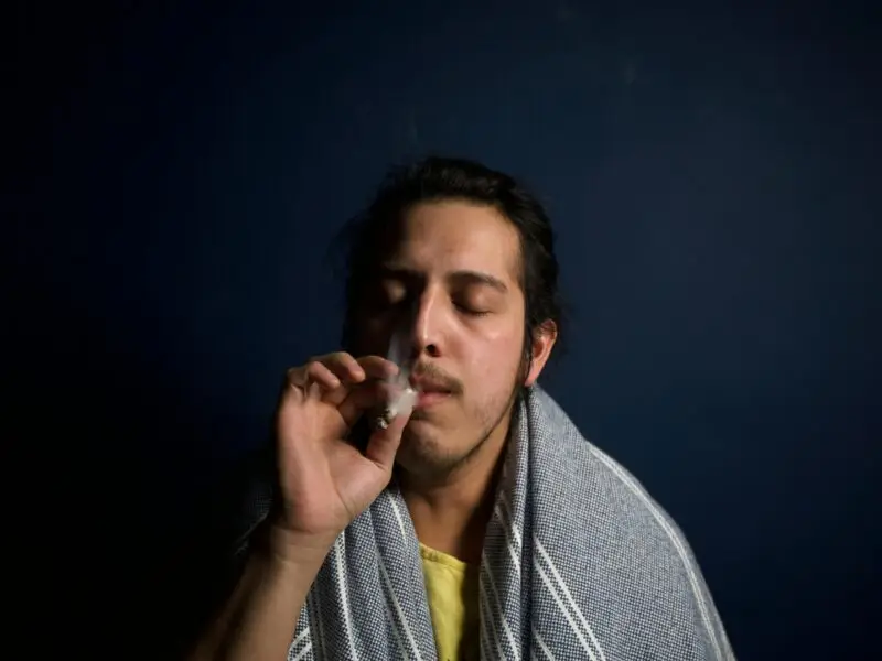 A man with a towel wrapped around his head smoking a joint