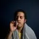 A man with a towel wrapped around his head smoking a joint