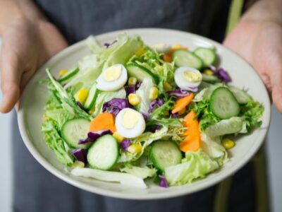 a man holding a salad with lots of nutritional vegetables.