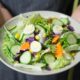 a man holding a salad with lots of nutritional vegetables.