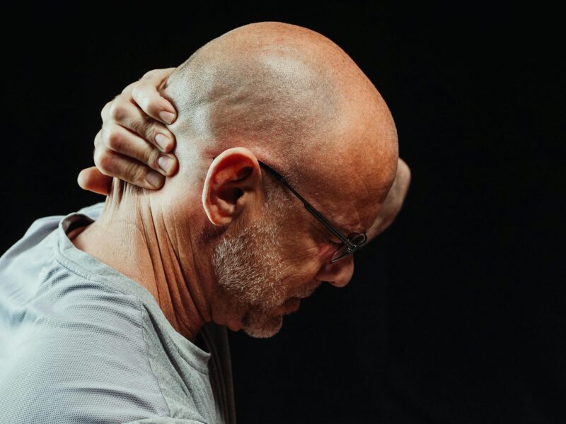 a man in pain grabbing his neck for relief.