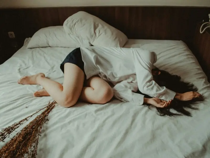 a woman laying in bed fully clothed going through recovery