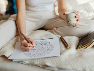 a woman sitting on a bed, drawing in a notebook