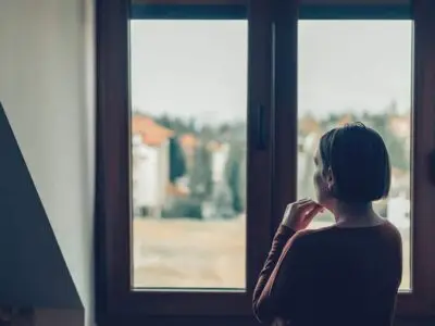 Person experiencing post-acute alcohol withdrawal symptoms, sitting with head in hands during recovery.