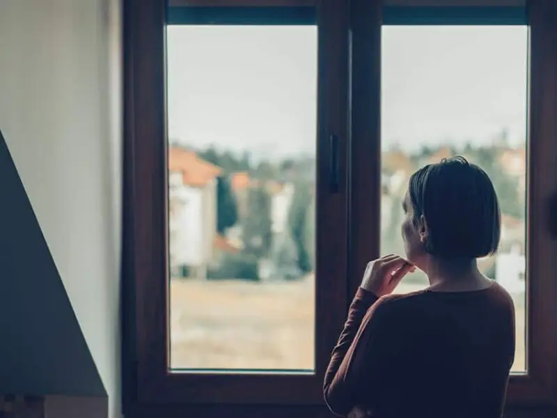 Person experiencing post-acute alcohol withdrawal symptoms, sitting with head in hands during recovery.