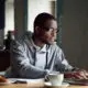 Serious young African American man using a laptop while sitting at a table.