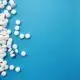Scattered white pills on a blue background, representing prescription drug dependence and medical detox treatment.
