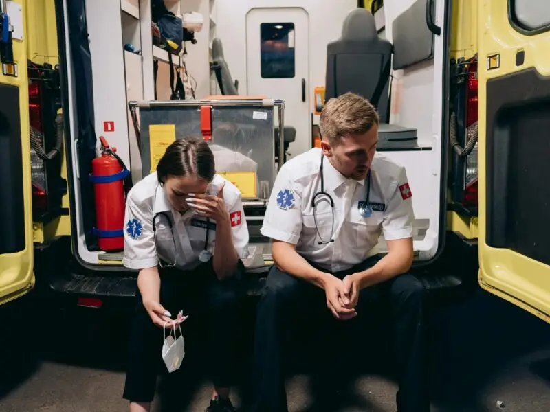 Two exhausted paramedics sitting in ambulance interior
