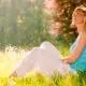 Woman relaxing against a tree in a sunlit meadow, reflecting peacefully during addiction recovery.