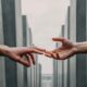 Two hands reaching toward each other between tall stone pillars, symbolizing support and connection in recovery.