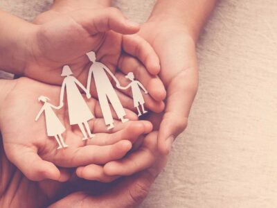 Cupped hands holding a paper cutout of a family, symbolizing family support in addiction recovery.